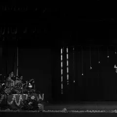 A black and white photo from my student's maiden Arangetram. It captures the grand scale of the stage, the live orchestra, and the solo dancer, a truly momentous occasion.