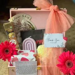 A 'Thank You' hamper designed to pamper and show appreciation. This gift is packed in a pink suitcase box and includes skincare items, a scented candle, and premium chocolates.