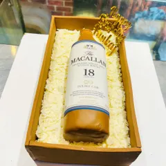 This hyper-realistic cake of a Macallan 18 Year Old whisky bottle is sculpted from cake and fondant, resting in an edible wooden crate filled with white chocolate shavings.