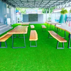 A covered outdoor seating area for a cafe or restaurant, floored entirely with artificial grass. It creates a comfortable, garden-like atmosphere for customers.