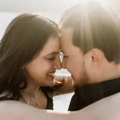 A beautiful, sun-kissed close-up of a couple. The backlighting creates a lovely halo effect, highlighting their smiles and the intimacy of the moment.