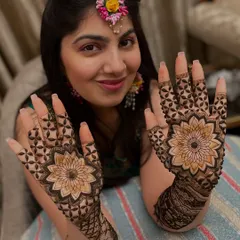 A radiant bride proudly displaying her stunning mandala mehandi. Her happy expression makes the artwork shine even brighter.