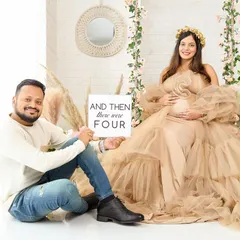 A fun and sweet family announcement photo. The couple is in our boho swing set, holding a sign that says "And then there were four," celebrating their growing family.