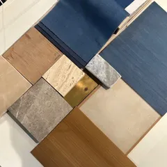 A material palette for a commercial workspace, featuring wood veneers, marble, brass, and blue fabric swatches. The brief was to create modern interiors with a touch of luxury, and this selection reflects that balance.