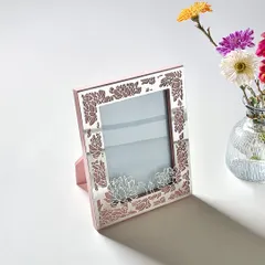 This photo frame has a soft pink enamel base with a delicate silver-plated floral cutout, creating a look that is both modern and romantic.