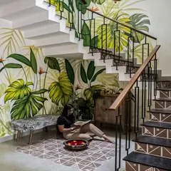 A creative use of the space under a staircase, featuring a beautiful, hand-painted tropical leaf mural. This design turns a typically underutilized area into a stunning and artistic focal point.