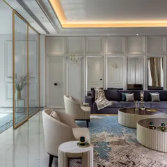 This living area is designed as a comfortable and centered space. The handpicked furniture, including a deep purple sectional and elegant armchairs, is arranged to encourage conversation, reflecting our commitment to luxurious simplicity.