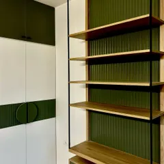 We designed this study and storage space with a mix of open shelving and closed cabinets in a striking olive green and white. The fluted green panel and custom circular handle add a unique, textural detail to the wardrobe.