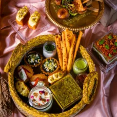 A closer look at a festive grazing platter, showcasing a mix of mini quiches, cheese straws, dips, and desserts, all beautifully arranged in a woven basket.