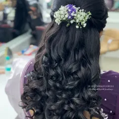 A beautiful example of a modern bridal hairstyle. These soft, voluminous curls are gathered into a half-updo and decorated with delicate flowers, perfect for a reception or engagement.