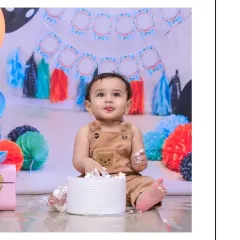 A moment of curiosity during a cake smash session. The baby looks up with a little frosting on his face, creating an adorable and funny memory of his first birthday.