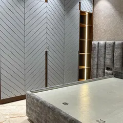 This bedroom features a large wardrobe with a modern chevron pattern on the doors. We integrated open, backlit shelving into the unit for decorative items or everyday essentials.