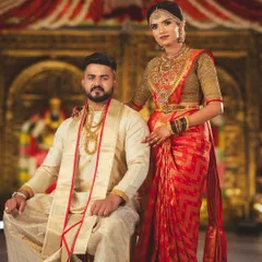 A royal portrait of the couple seated at their wedding ceremony. The decor is inspired by temple architecture, with ornate golden backdrops and traditional attire.