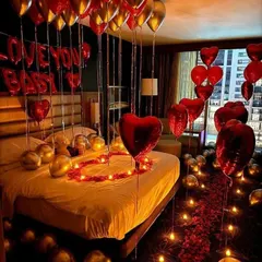 For a truly romantic gesture, we can transform any room into a luxurious retreat. This surprise setup includes a candle-lit rose petal pathway, heart-shaped balloons, and "I Love You Baby" foil letters sentimientos on the bed.