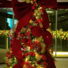 A close-up of the opulent Christmas tree, glowing with warm lights and covered in rich red and gold decorations.