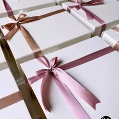 A sea of white boxes, each tied with a beautiful satin ribbon. This is what a large custom order looks like before it heads out to bring smiles to many faces.