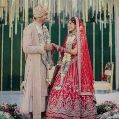 The full bridal look for Jigisha. Her traditional red lehenga is complemented by makeup that is both classic and modern, with a flawless base that lasts through the entire ceremony.