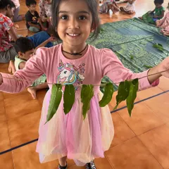 A child proudly displays her handmade 'toran' made from real leaves. This simple craft connects children to nature and our cultural traditions of decorating our homes for festivals.