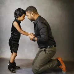 A powerful and emotional portrait of a father and daughter. The simple grey backdrop and matching black outfits put all the focus on their deep connection.