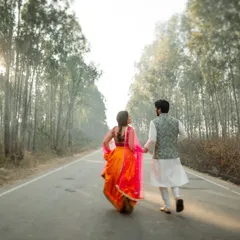 A romantic pre-wedding shot of a couple walking hand-in-hand down a tree-lined road. The beautiful light and natural setting create a timeless and cinematic feel.