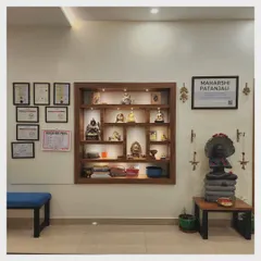 Our reception features a display shelf with sacred statues and books, and our wall of certifications. To the side sits a statue of Maharshi Patanjali, the codifier of the Yoga Sutras, who oversees our shala.