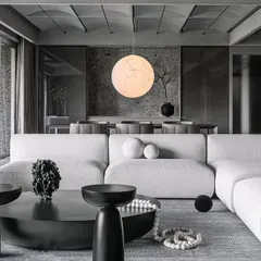 We designed this expansive living room as a large cuboidal volume, using architectural elements to manage its scale. The ceiling is subdivided into quadrants, with dramatic vaults that draw the eye and create a sense of rhythm, an approach that renders the design intent authentic. The refined grey scale palette is softened by plush, minimalist furniture and a statement spherical pendant light, establishing a dialogue between the living and dining areas.