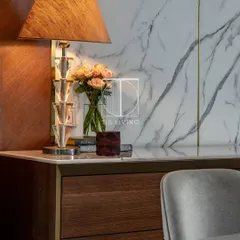 A close-up of the dining area, showing the beautiful veining of the Michelangelo stone and the custom-made wooden credenza. The warm lighting highlights the rich textures and craftsmanship.