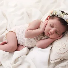 A little angel, dreaming sweetly. This newborn portrait with a delicate floral crown and soft, lacey outfit is all about capturing innocence. The simple, clean background keeps all the focus on your baby's serene beauty.