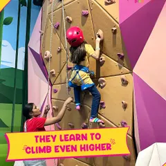 With the help of our Play Pals, kids learn to climb even higher. This image shows a staff member carefully guiding a child on the rock wall, helping her build confidence and skill in a secure setting.