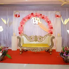 A beautiful engagement stage with a pink floral ring, a custom couple's initial, and elegant white and gold seating.
