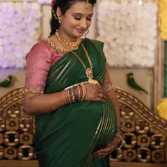Sheetal cradling her baby bump during her Seemantha ceremony. The makeup is soft and traditional, designed to give her a beautiful, maternal glow.
