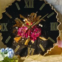 For a touch of drama, this clock features a black face with a central cluster of preserved pink and gold flowers. The gold Roman numerals and hands complete the luxurious look.