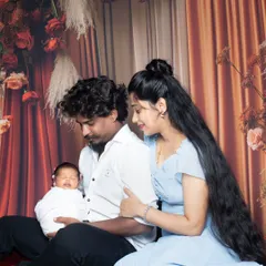 A peaceful family portrait with parents admiring their sleeping newborn, swaddled in white.