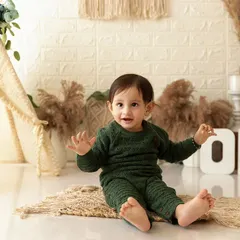 A wide shot of the boho-themed cake smash setup, showing the baby boy sitting happily before the cake arrives.