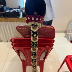A detailed look at a bridal poola jada, where the braid is decorated with fresh jasmine, red velvet flowers, and traditional temple jewelry. This style is a hallmark of South Indian bridal beauty.