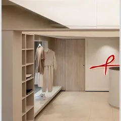 The store layout is designed to be open and uncluttered, with integrated shelving and display areas. The neutral color palette allows the merchandise to stand out, while the red brand logo provides a strong visual anchor.