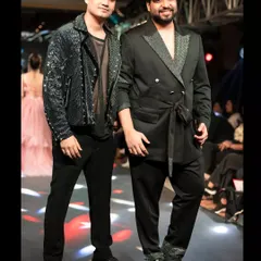 On the runway with my showstopper, Deep. I styled him in a black sequined jacket over a sheer top for a look that is both edgy and glamorous, perfect for high-fashion menswear.
