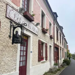 The charming storefront of "Le Secret des Artistes" in a French village. The textured facade, rustic shutters, and wrought-iron sign are beautiful examples of how simple, authentic details create timeless character.