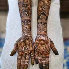 This design is a tribute to family bonds. The palms feature a varmala ceremony portrait and a family portrait of the bride with her parents and sister, with their names 'aai-baba' and 'didi' written on the fingers.