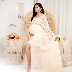 A graceful solo portrait in a boho-inspired setting. The mother-to-be, in a beautiful lace dress, looks elegant and serene surrounded by macrame and neutral tones.