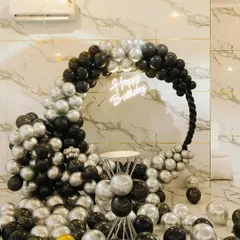 A chic and modern birthday setup with a black and silver balloon ring. The 'Happy Birthday' neon sign adds a cool touch, making it perfect for an adult's birthday party.