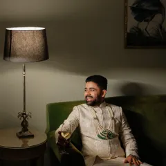 A relaxed portrait of the groom enjoying a quiet moment with a drink before the festivities begin.