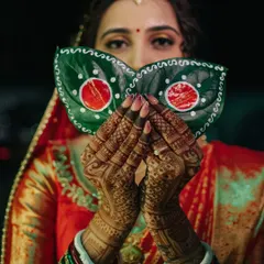 A mysterious and culturally rich portrait of a Bengali bride, her face partially hidden by decorated paan leaves, highlighting intricate mehndi and traditional details.