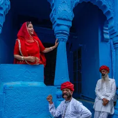A lively scene in Jodhpur's blue city, with men in traditional attire and a woman in a red saree adding a splash of contrasting color. This frame is a perfect example of Rajasthani street life.