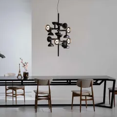The Sibilla chandelier by Karman, with its intersecting arms and multi-directional lights, hangs over a dining table. This piece, inspired by Dutch neoformalism, acts as a complex geometric sculpture, diffusing light in all directions.