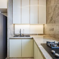 A close-up of the sink and hob area. The seamless look is achieved by using the same exotic Brazilian stone for both the countertop and the backsplash.
