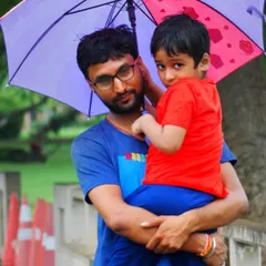 A close-up portrait of a father holding his son securely under an umbrella. This image captures the protective and loving bond in a natural, unposed family portrait.