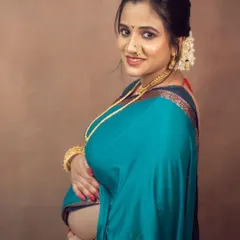 A glowing close-up portrait of a mother-to-be in a traditional Maharashtrian look, her smile radiating happiness and anticipation.