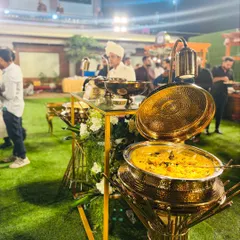A close-up of the aromatic Mutton Mandi being served from a traditional, ornate golden pot. The focus is on the rich, flavorful rice and tender meat.