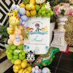 This welcome sign for Anant's mundan ceremony introduces the jungle theme with cute animal characters and a vibrant balloon arrangement.